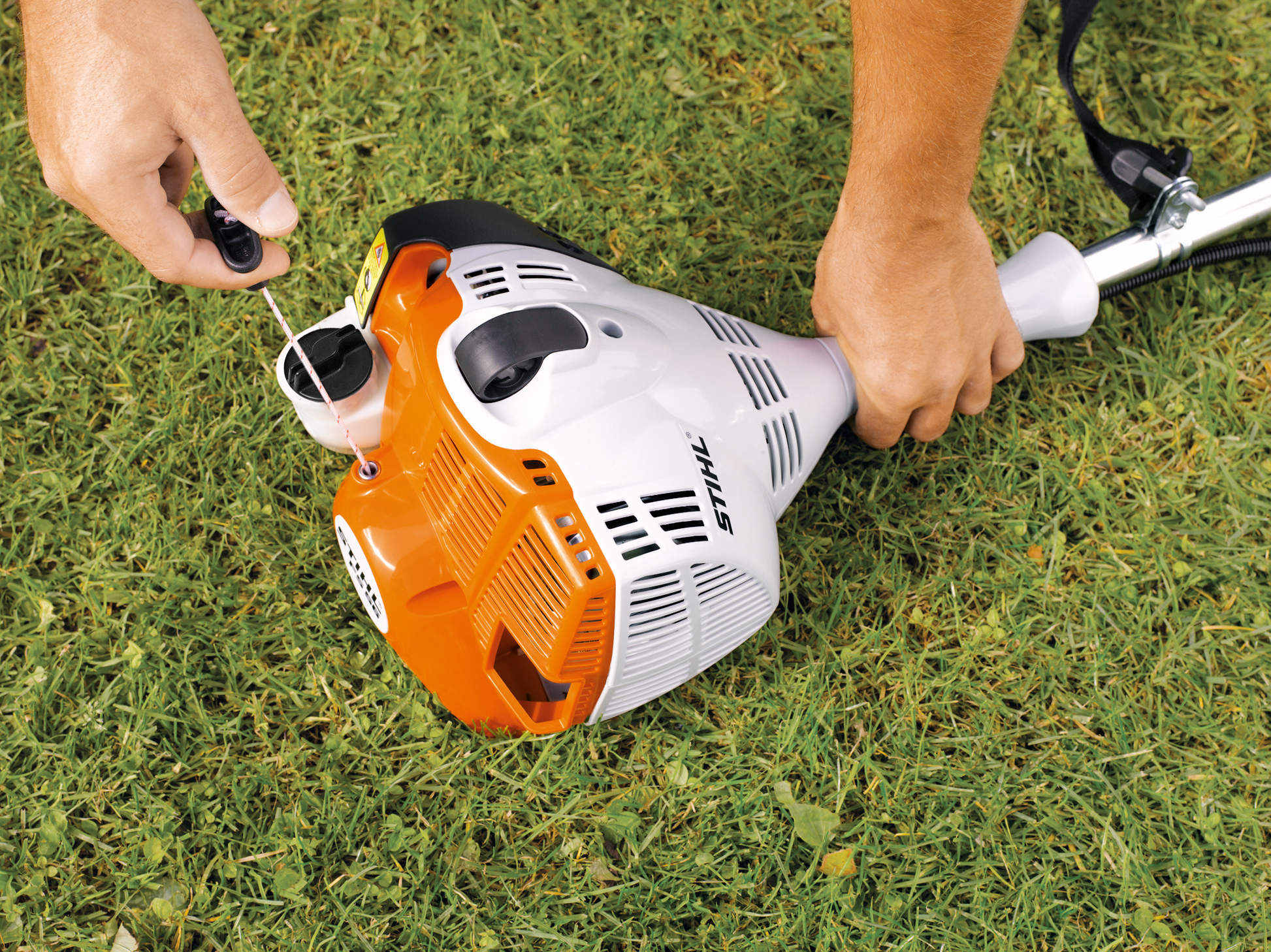 A close up image of someone starting up the STIHL FS 40 Strimmer on the ground