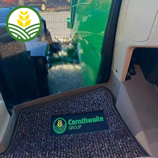 The green and yellow Cornthwaite Group logo embroidered on a brown carpet tractor floor mat